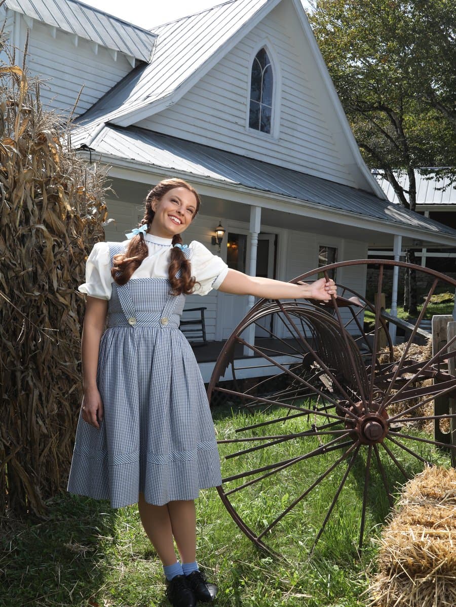Dorothy at Land of Oz beside an antique wagon wheel