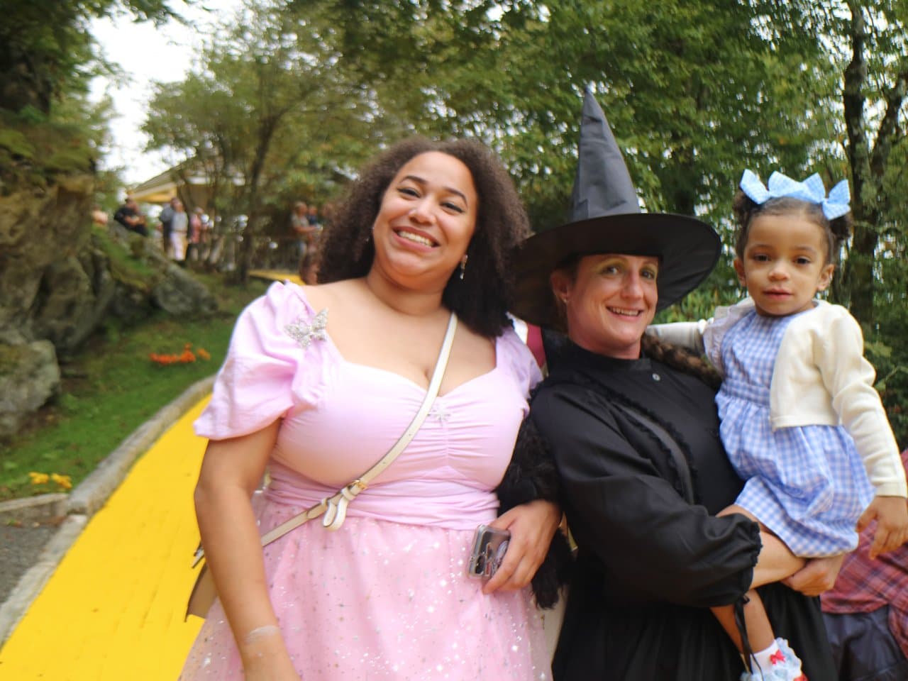 Park guest in pink with the Wicked Witch holding a child in Dorothy's gingham dress